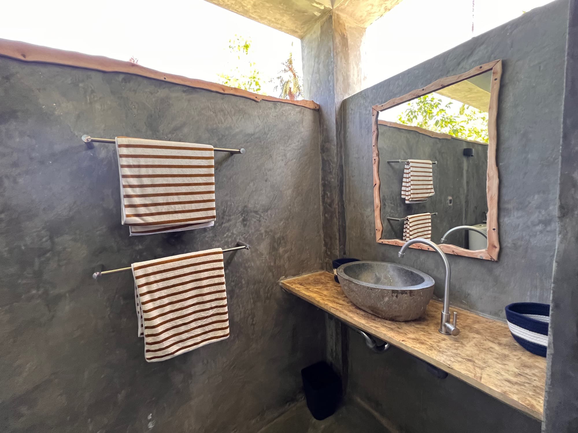 A poured-concrete bathroom with a stone basin