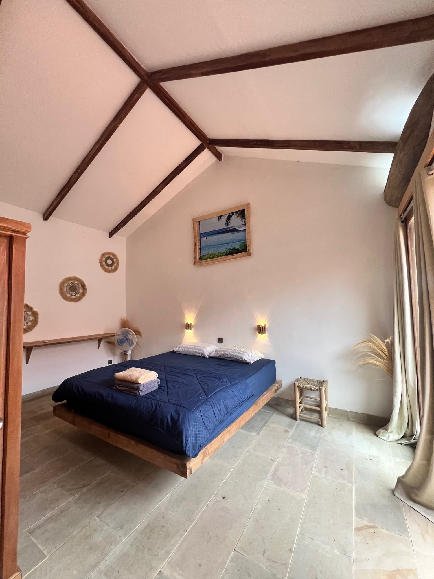 A villa bedroom under the beams, with a hanging timber bed
