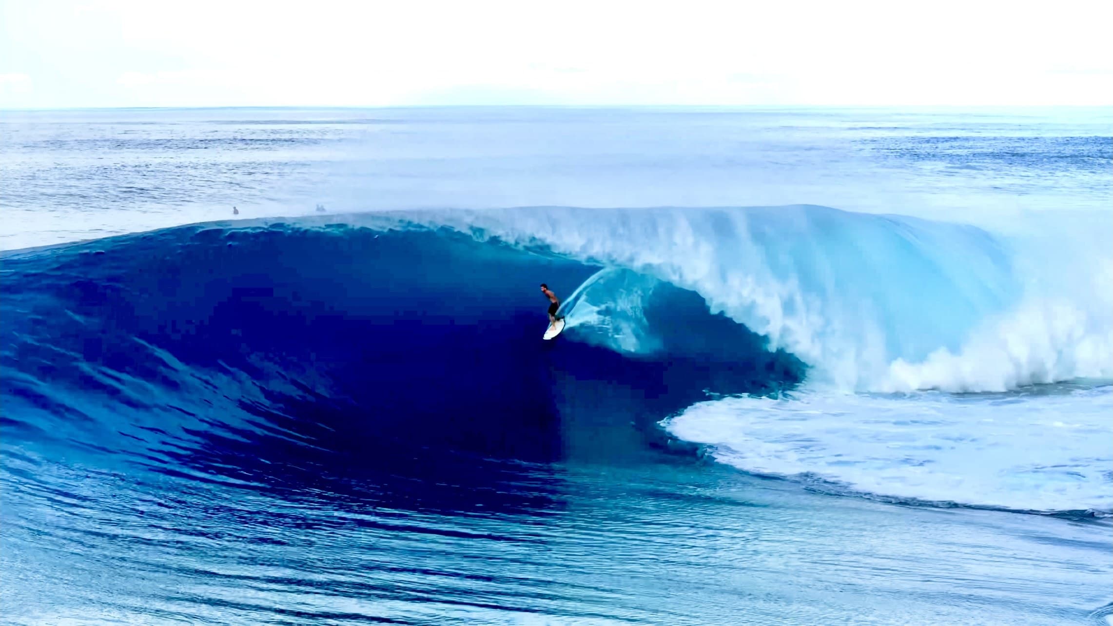 Deep blue water and a surfer setting his line under the lip
